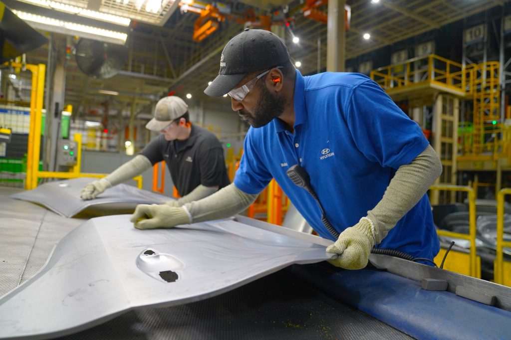 two workers making car parts in a factory